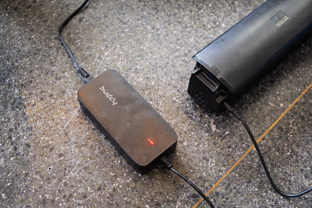 Elsykkelbatteri og lader som lader på gulvet